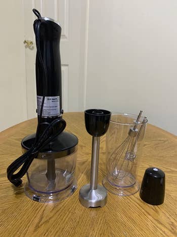 reviewer showing all the attachments of the immersion blender set