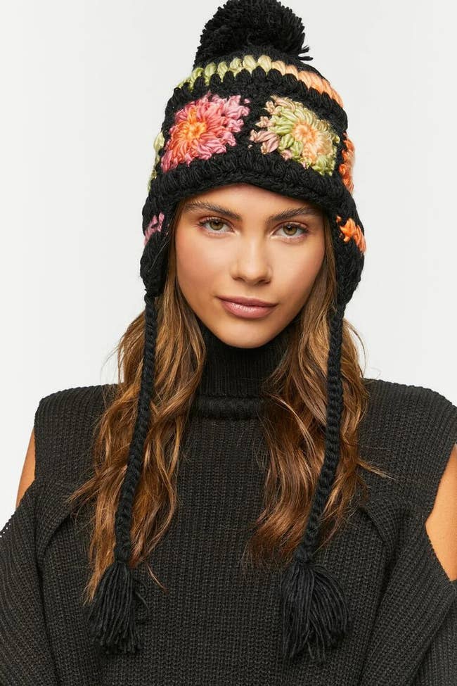a model posing in the black, pink, and green beanie