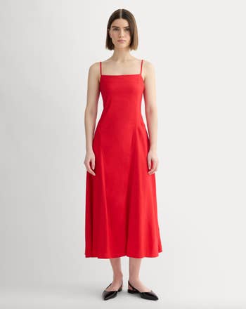 Person wearing a sleeveless, fitted reddish  formal  with spaghetti straps, lasting  successful  a neutral pose