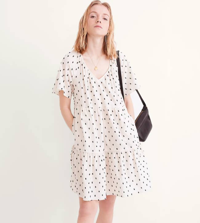 a model in an off white v-neck t-shirt dress with black mini textural dots