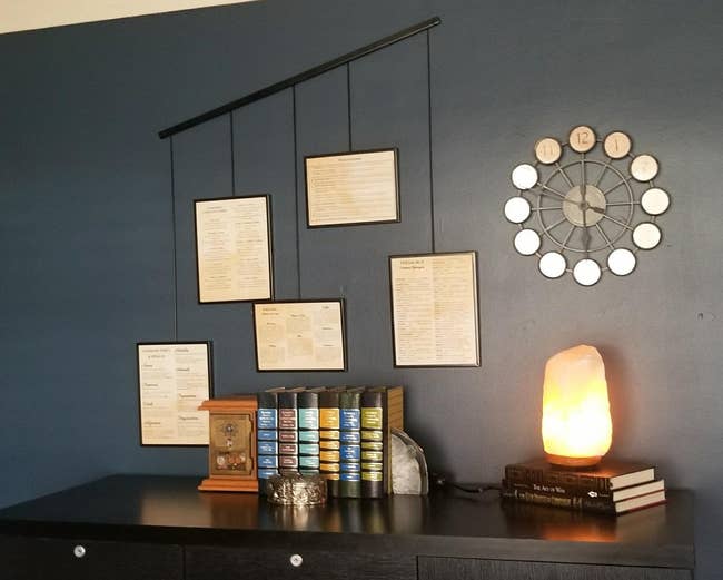 reviewer's wall-mounted frames above a cabinet with decor items, including a lit salt lamp and organized stacked books