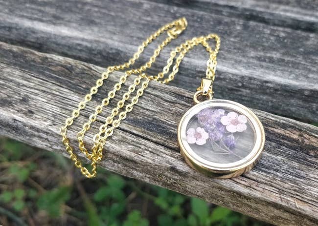 The gold chain with clear round pendant with purple flowers inside