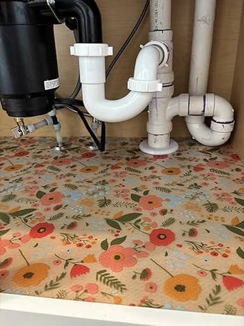 Floral-patterned support  liner covers the bottommost  of a room  descend  cabinet, providing a decorative and protective layer