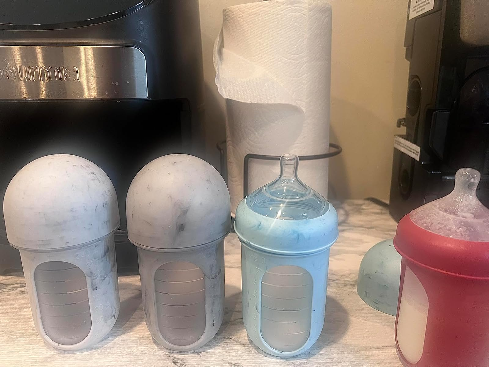 three bottle frames in shades of gray and blue with silicone inserts and nipple lids 