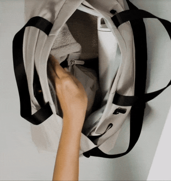 model placing a laptop into the packed bag and zipping it up