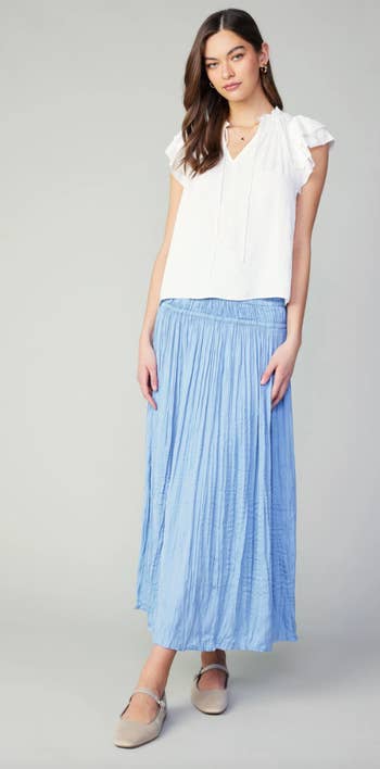 Model in a white blouse and blue pleated skirt with espadrille flats. Perfect for a spring wardrobe update