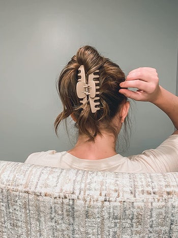 A customer review photo of a person wearing a pink claw clip that's holding up their hair