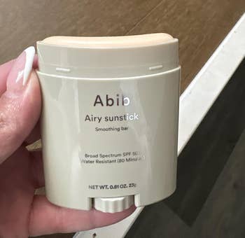 Hand holding an Abib Airy Sunstick Smoothing Bar, SPF 50+, water-resistant for 80 minutes
