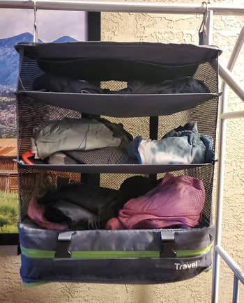 a reviewer photo of the hanging organizer filled with clothes 