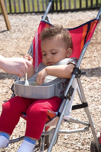 a baby eating food out of the bib tray 