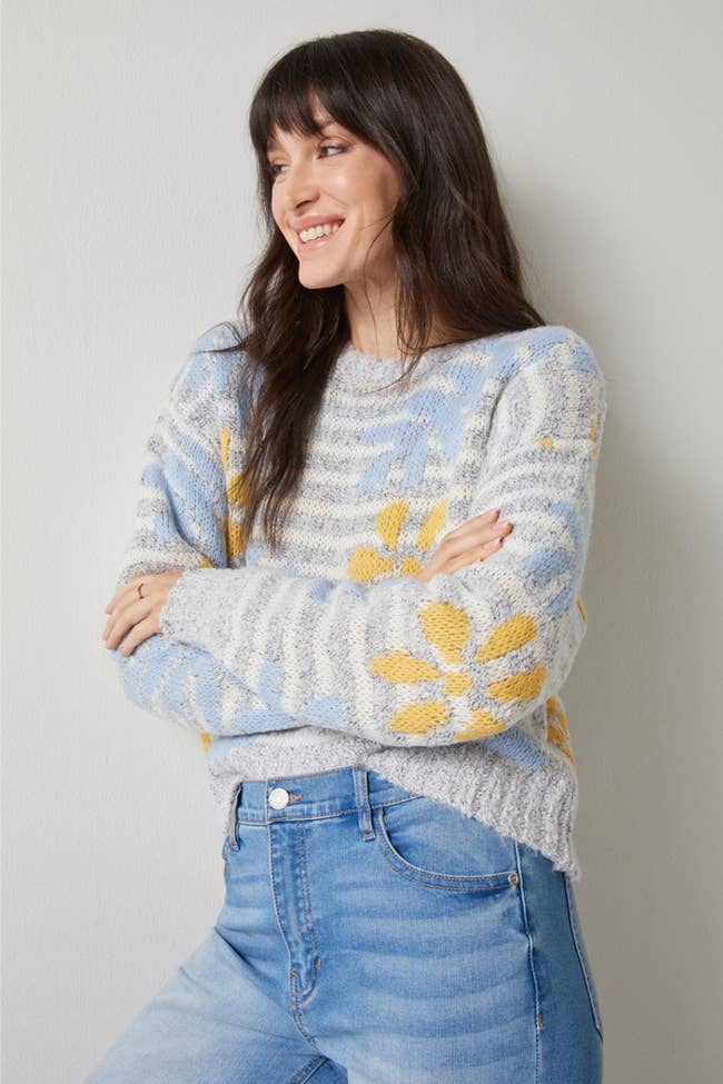 model in gray striped sweater with yellow and blue flowers