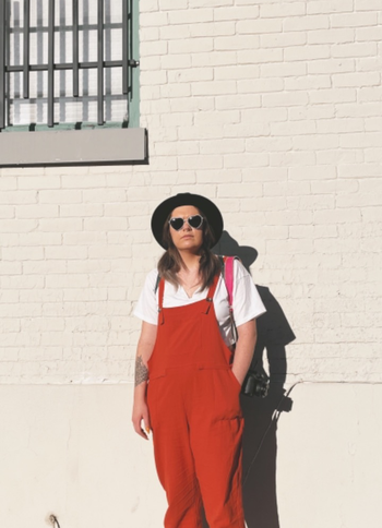 reviewer in the brick red colored overalls