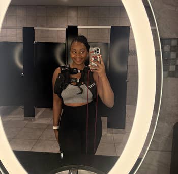 Person successful gym attire with a telephone strapped to their chest, taking a reflector selfie successful a restroom
