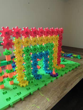 Toy operation  acceptable   with interlocking gears and blocks forming an arch connected  a greenish  base, demonstrating an interactive gathering  enactment   for children
