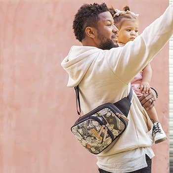 model holding a child with the sling diaper bag around their chest