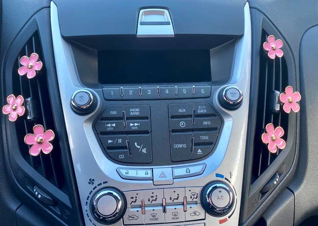 reviewer photo of pink daisy clips on their car vent