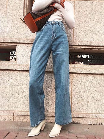 a model wearing high waisted wide leg blue jeans