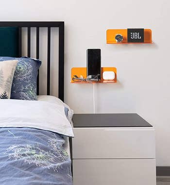 the orange shelves hanging above a nightstand