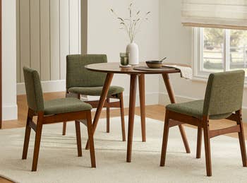 Four mid-century contemporary dining chairs round a minute round table in a honest-toned room