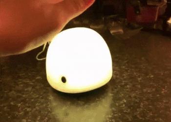 A reviewer tapping on a whale nightlight to change its colors 