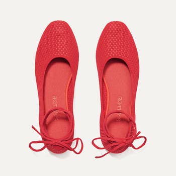 A pair of red ballet flats with tie-up detail