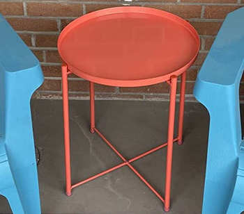 reviewer photo of the red table on a patio next to two blue deck chairs