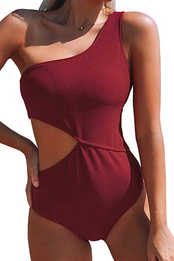 model in red one shoulder suit with cutout on one side of the torso