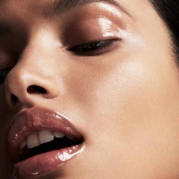 Close-up of a model's glossy makeup look, focusing on shimmering eyeshadow and shiny lip gloss