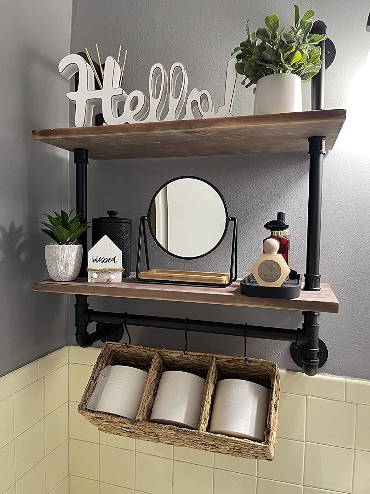 Reviewer image of brown and black pipe two-tier shelf with toilet paper hanging from S hooks