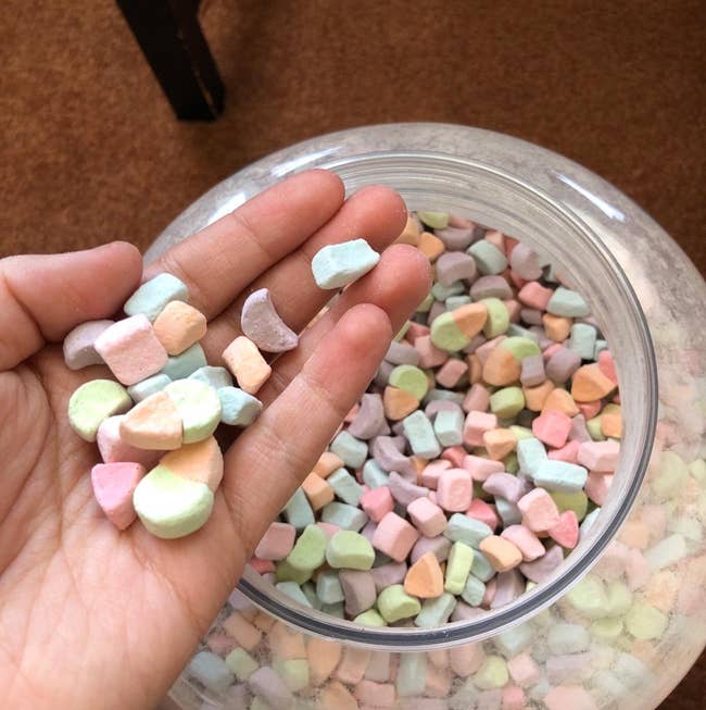 reviewer holding some marshmallows next to the jar