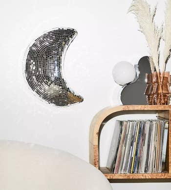 the disco moon hanging on a wall next to a wooden shelf