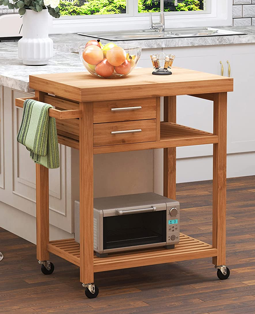 Bamboo microwave cart with two drawers and a towel rack on hardwood floor in kitchen