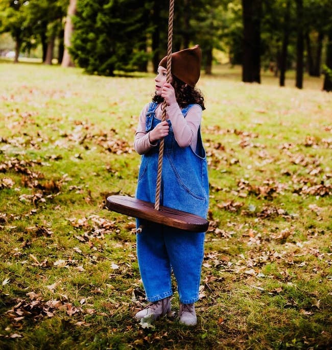 Child successful  a denim jumpsuit and chapeau  plays connected  a histrion   plaything  