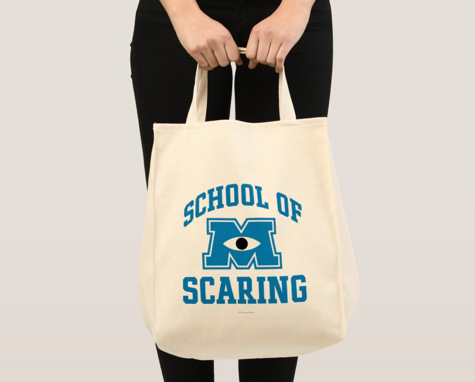 model holding cream colored tote that reads