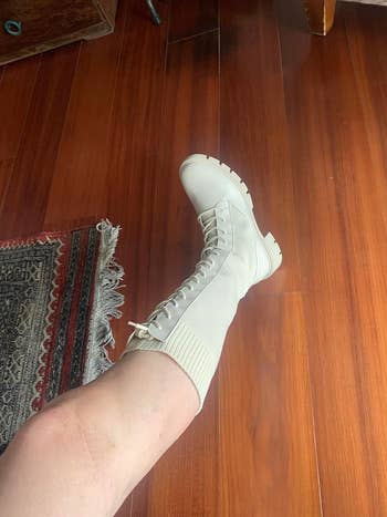A reviewer showing one of their legs while wearing the boot in a cream color