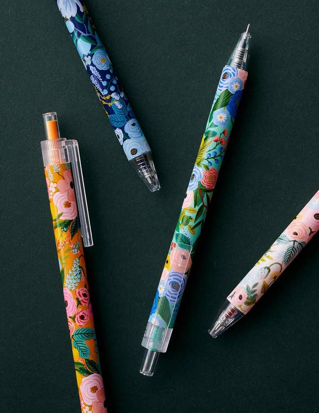 Assorted pens with floral patterns arranged on a flat surface