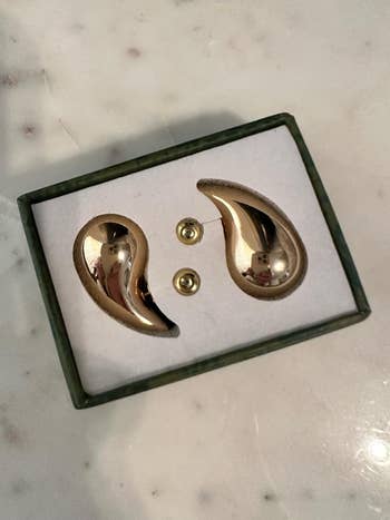 A acceptable   of golden  earrings placed successful  a greenish  rectangular box