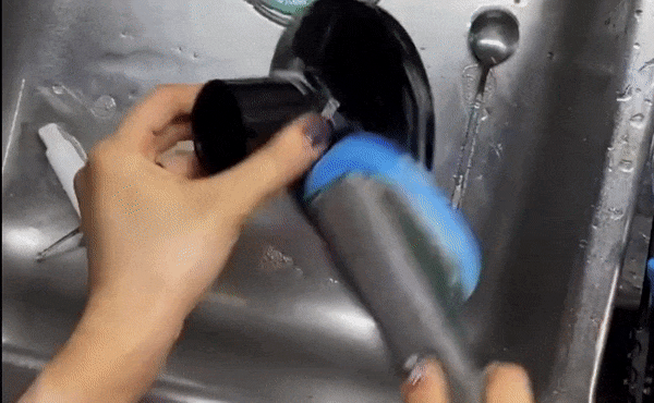 A reviewer washing dishes with the Scotch-Brite dishwand