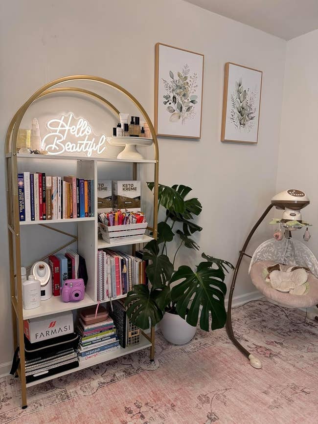 A stylish room with a gold arch bookshelf, books, a 