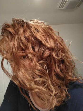 Close-up of a person's wavy, textured hair flowing over their face, showcasing a natural, voluminous hairstyle