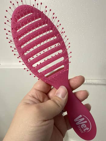 Hand holding a Wet Brush hairbrush with a slotted, flexible bristle design
