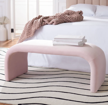 pink curved bench at the food of a bed