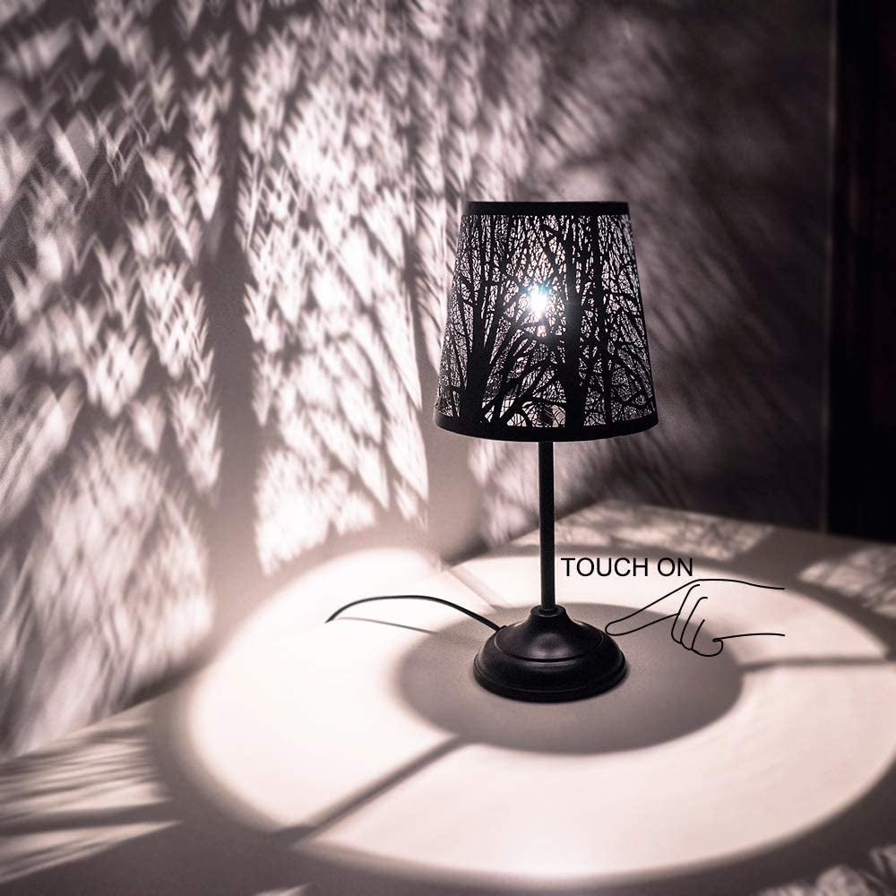lamp with a shade that casts a spooky forest design on the walls