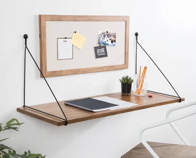 Wall-mounted desk with stationary and bulletin board holding notes and a photo