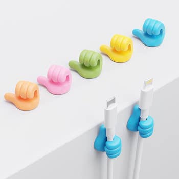 several of the colorful thumbs up cord organizers on a white surface