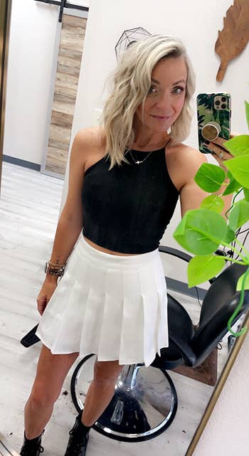 reviewer wearing the white pleated skirt with a black tank