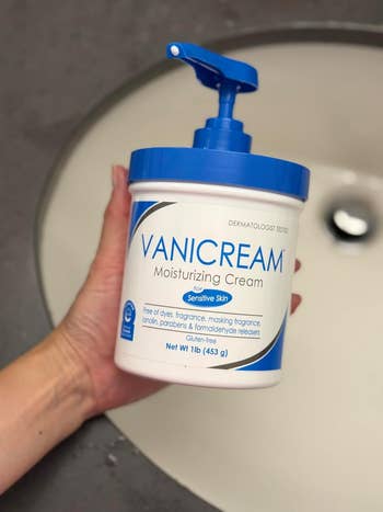 A manus  holds a 1 lb jar of Vanicream Moisturizing Cream for delicate  skin, highlighting its dermatologist-tested and free-from characteristics