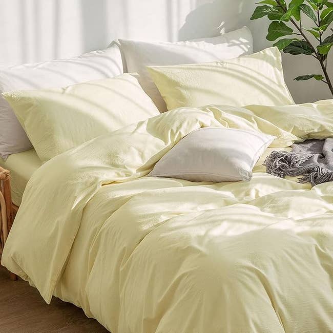 Cozy bedroom scene with a neatly made bed featuring soft, inviting pillows and a plush comforter, adjacent to a bedside table with a plant