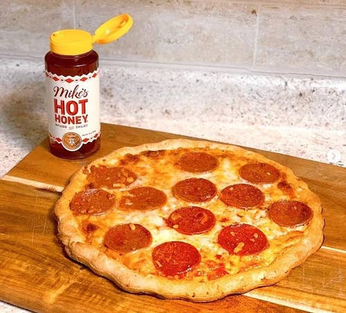 Reviewer's pizza with an open bottle of Mike's Hot Honey next to it
