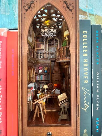 Intricate mini room diorama acceptable betwixt books, featuring a elaborate interior with a table, bookshelves, and creation supplies